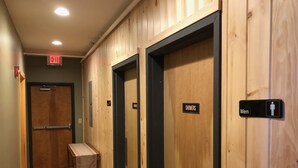 A hallway with wooden walls, a bench, and doors labeled "SHOWERS" and "Men".