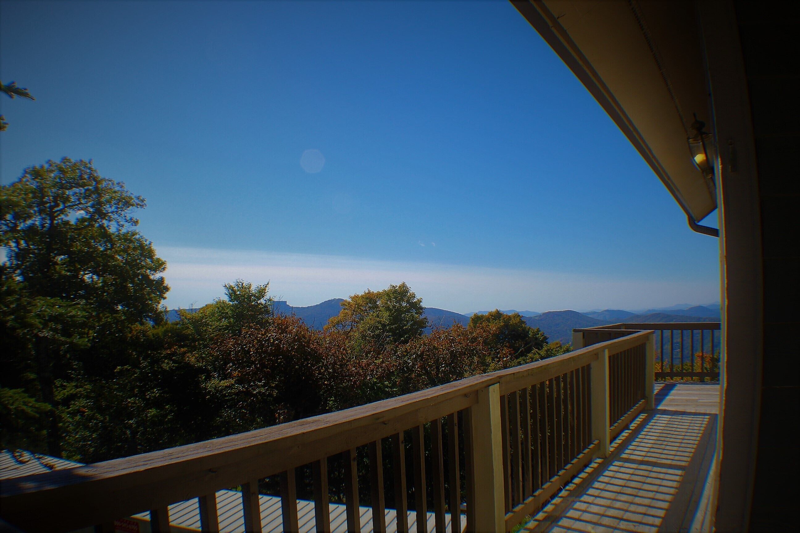 Un balcon doté d’une balustrade en bois, offrant une vue sur un paysage montagneux.