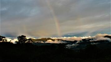 A mountain landscape with a rainbow and clouds.