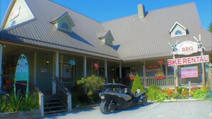 A building with a metal roof, a porch, and a sign for a BBQ and bike rental.