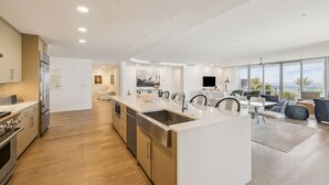 Una cocina moderna con una isla central, electrodomésticos de acero inoxidable y un amplio ventanal con vista al océano.