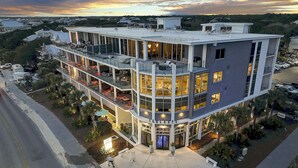 Un hotel de varios pisos con terraza en la azotea, mobiliario exterior y vistas del paisaje circundante.