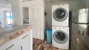 Eine kompakte Küche mit Waschmaschine, Kühlschrank und Mülleimer.