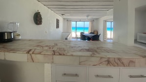 Eine Küche mit Marmorarbeitsplatte, einem Mixer und Blick auf den Strand.
