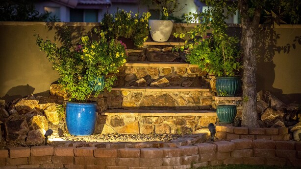 A stone staircase with potted plants, surrounded by a brick wall and a tree. - Quiet & Cozy Large home with big backyard & Pool (Tucson)