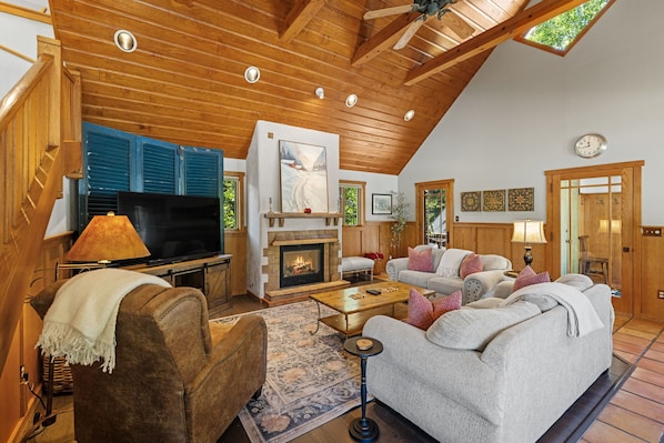 A cozy living room with a fireplace, wooden ceiling, and a television.