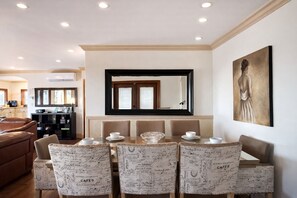 A dining area with a table set for four, a large mirror above the table, and a framed artwork on the wall.
