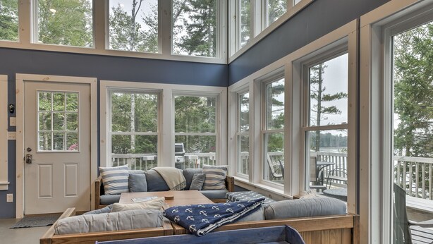 A cozy room with a large window, a wooden bench, and a cushioned seating area. - Enjoy the quiet, the calm, the sunset and the deck! (Cushing)