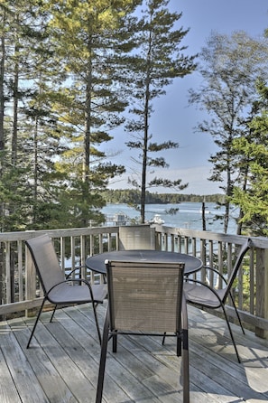 Enjoy a serene lakeside view from this deck, surrounded by tall trees and a picturesque dock.