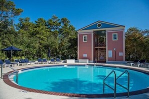 Ein Pool mit Liegestühlen und ein Gebäude mit einem Balkon.