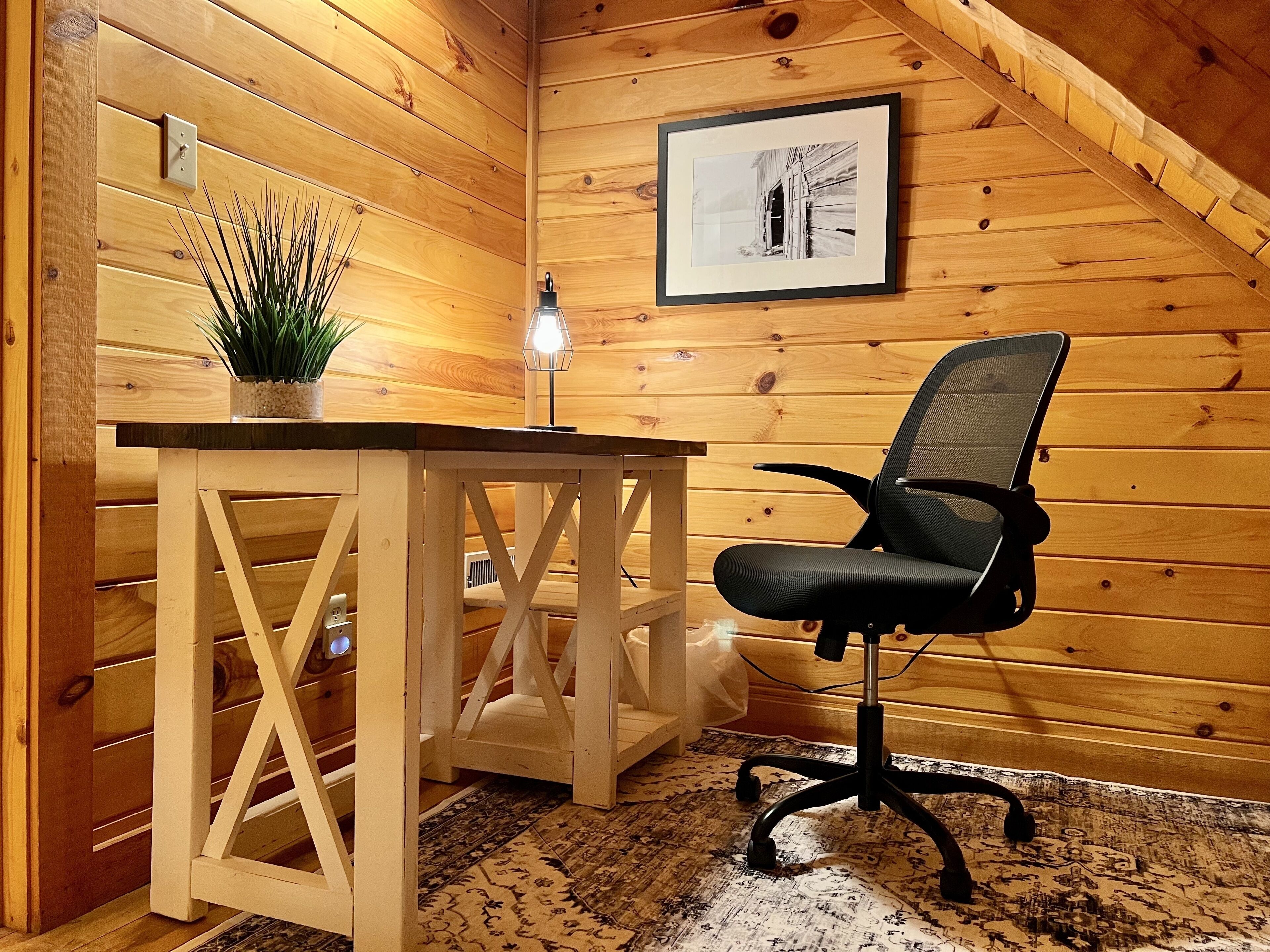 Een houten interieur met een bureau, stoel en een ingelijst kunstwerk aan de muur.