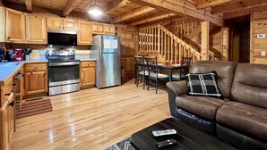 A wooden cabin interior with a kitchen, dining area, and living room.