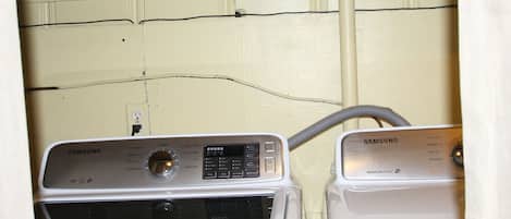A laundry area with two washing machines, a shelf with a 'Laundry' sign, and a box of tissues.