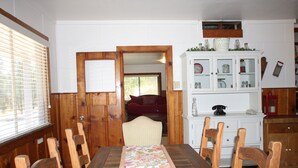 A dining area with a wooden table and chairs, a patterned table runner, and a white cabinet with glass doors. - Midpines Hwy 140 House on your way to Yosemite (Midpines)