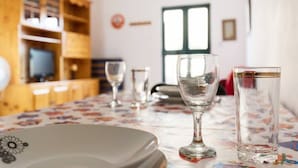 A dining table with a floral tablecloth, a wine glass, and a tall glass. - Modern, Bright and spacious Apartment close to beach and st. Julians (Naxxar)