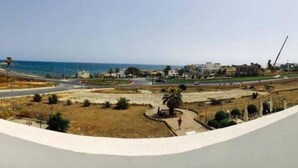 A coastal view with a road curving around a landscaped area, palm trees, and buildings in the background. - Modern, Bright and spacious Apartment close to beach and st. Julians (Naxxar)
