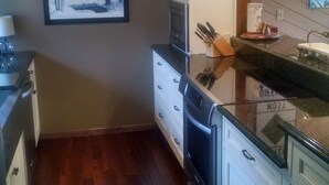 A kitchen with wooden flooring, white cabinets, a dishwasher, and a microwave.