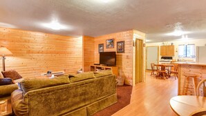 Una sala de estar acogedora con sofá, televisor y comedor con muebles de madera.