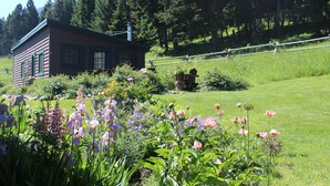 A log cabin with a garden in front, surrounded by trees. - Charming Log Cabin In Beautiful Cottonwood Canyon, Just Outside of Bozeman (Bozeman)