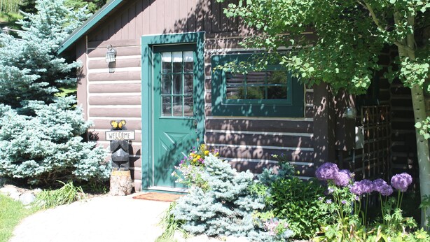 A log cabin with a green door, a welcome sign, and a window. - Charming Log Cabin In Beautiful Cottonwood Canyon, Just Outside of Bozeman (Bozeman)