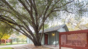 A building with a red door, a wooden fence, and a large tree in front. - 1 Min from Sequoia National Park Cabin for 2 with additional sleeper sofa (Three Rivers)