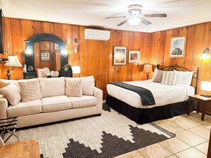 Cozy retreat with a traditional bed, sofa, and ceiling fan.