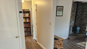 Un couloir avec un plancher en bois, une bibliothèque, une porte et une cheminée avec une hotte.
