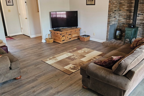 Living room with big screen TV, couch, love seat and glider chair.