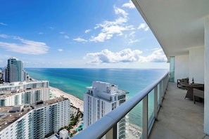 A high-rise building with a balcony overlooking a beach and ocean.