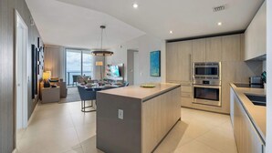 A modern kitchen with a central island, built-in appliances, and a dining area with a view. - 2 Bedroom Ocean View Escape with Premium Amenities (Hollywood)