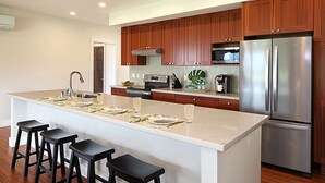 Una cocina moderna con armarios de madera, un refrigerador de acero inoxidable e una isla central con taburetes de bar.