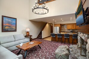 A spacious living area with a sofa, coffee table, and a painting on the wall. - Montaneros - Vail Adventure Base: Eat, Ski, Shop, Relax in Comfort (Vail)