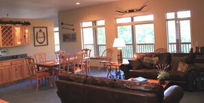 A spacious living room with a dining area, large windows, and a fireplace.