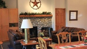 A living room with a fireplace, leather sofas, a dining table, and a lamp.