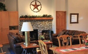 A living room with a fireplace, leather sofas, a dining table, and a lamp.