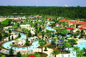 Un complexe hôtelier doté de plusieurs piscines, de palmiers et d’un grand bâtiment surmonté d’un toit rouge.