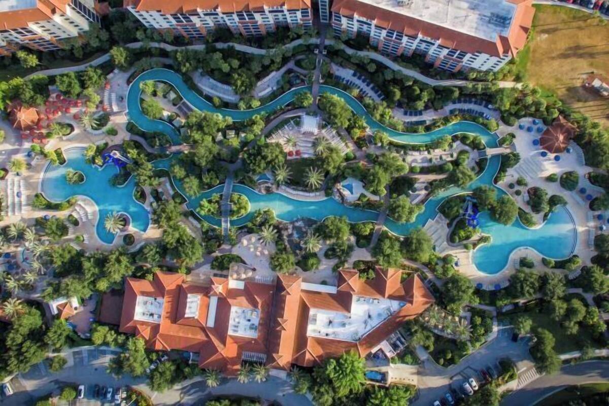 An aerial view of a resort with multiple swimming pools, landscaped areas, and hotel buildings.