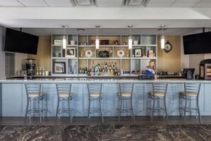 A bar area with a counter, bar stools, shelves with bottles, and a television screen. - Holiday Inn Club Vacations AT ORANGE LAKE RESORT by IHG (Winter Garden)