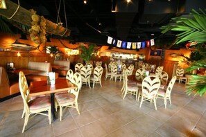 Um restaurante com cabines e mesas, algumas com cadeiras, e um balcão.