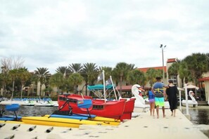 A dock with boats, a water body, and a row of palm trees. - Holiday Inn Club Vacations AT ORANGE LAKE RESORT by IHG (Winter Garden)