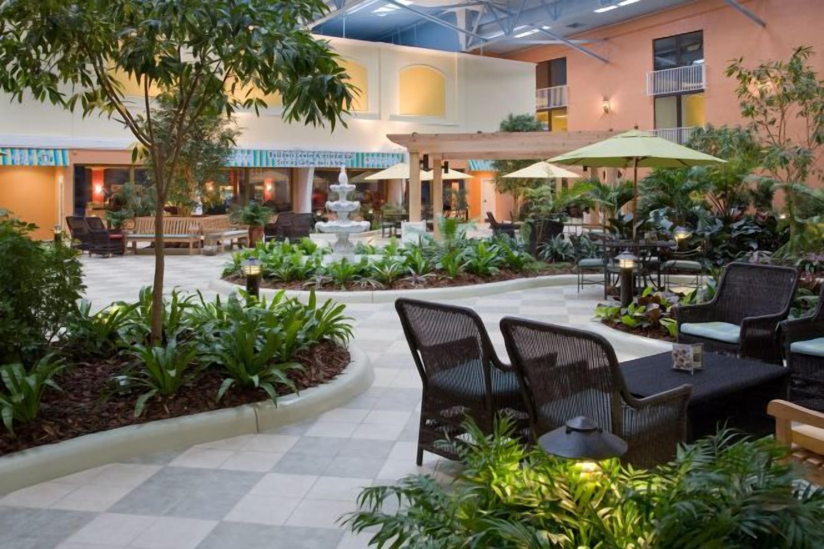 Un patio interior con zonas de estar, una fuente y plantas en macetas.