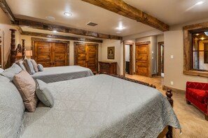 Habitación de hotel con dos camas, armarios de madera, una silla roja y un espejo grande.