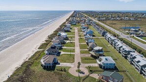 A coastal residential area with houses aligned along a beachfront, featuring a central road and a beach access path. - Beautiful view of the beach, 3 bedroom-3 full bath, WiFi, cable, big deck (Galveston)