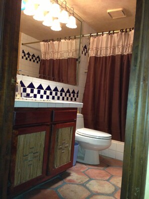 A bathroom with a toilet, a sink with a mirror, and a shower curtain.