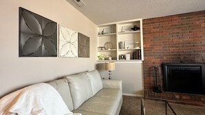 A living room with a white leather sofa, a fireplace, and decorative wall art. - Heritage Suites 44 (Manhattan)
