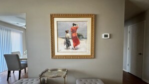 A living room with a framed painting, two grey ottomans, a small metal table, and a white door. - Heritage Suites 44 (Manhattan)