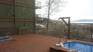Eine Holzterrasse mit Whirlpool und Blick auf eine gebirgige Landschaft.