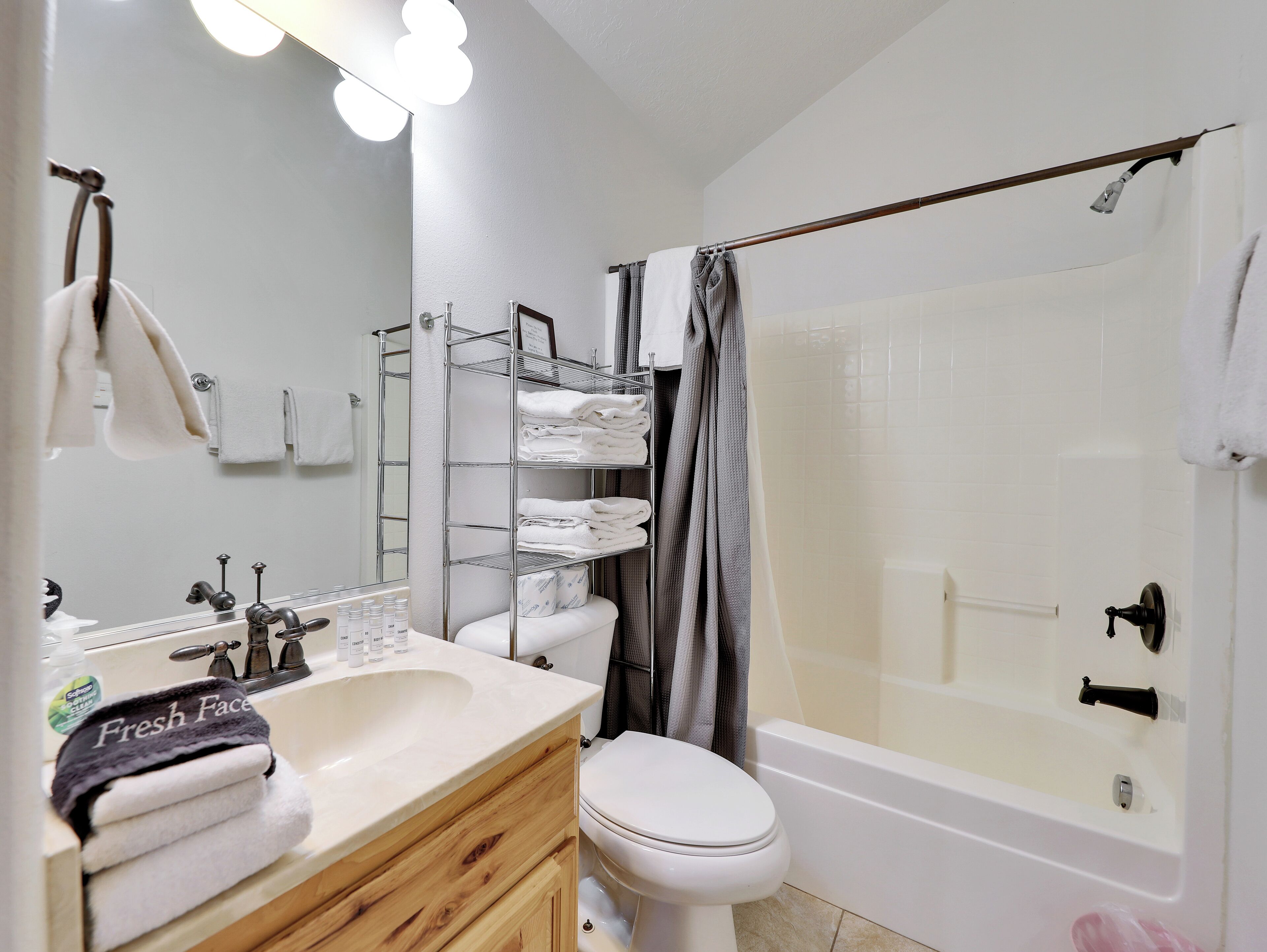 A bathroom with a white sink, a toilet, a shower with a glass door, and a towel rack with neatly folded towels.
