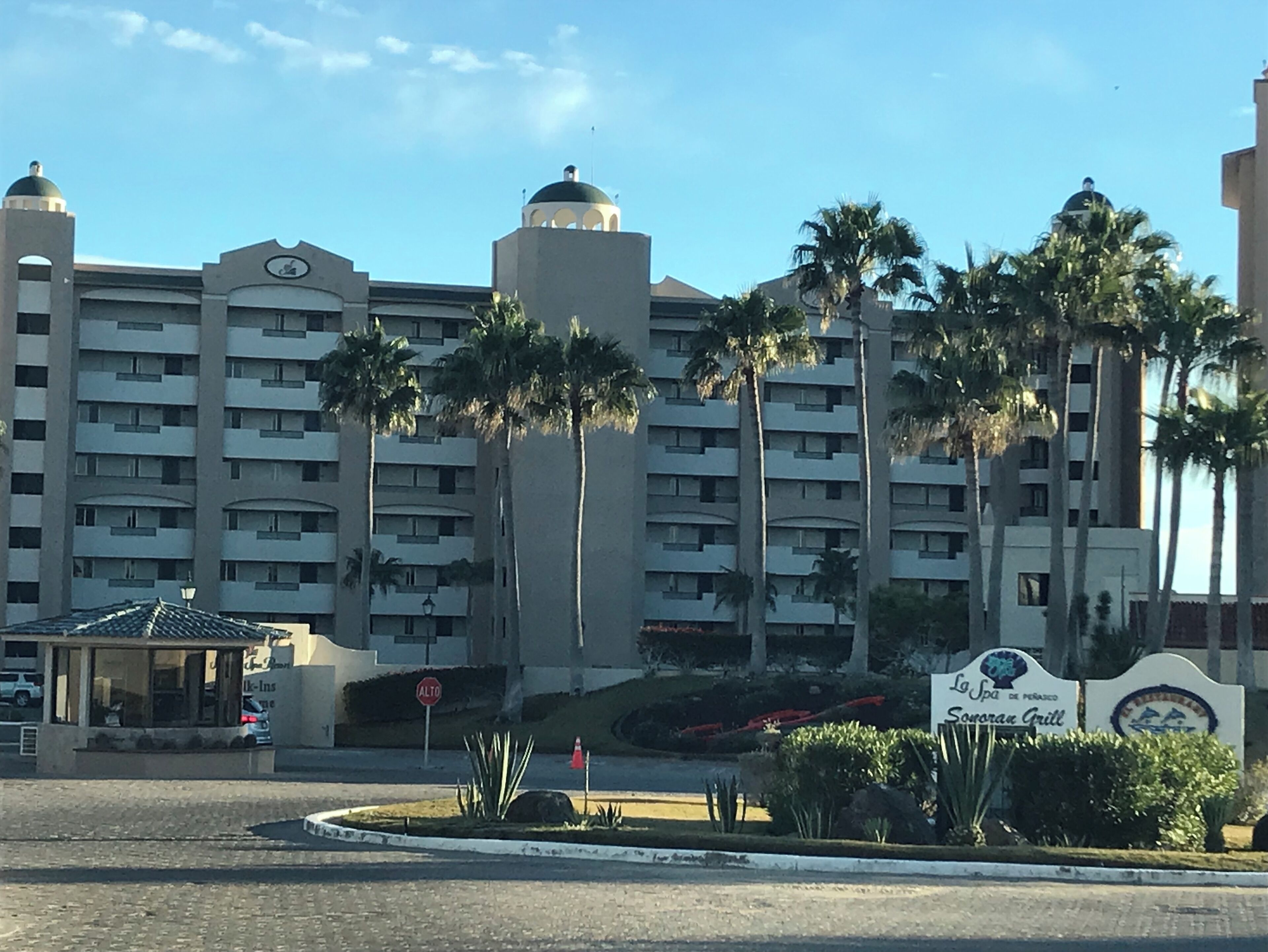 Un hôtel à plusieurs étages, doté d’un dôme central, de palmiers et d’une enseigne indiquant « Sonoran Grill ».