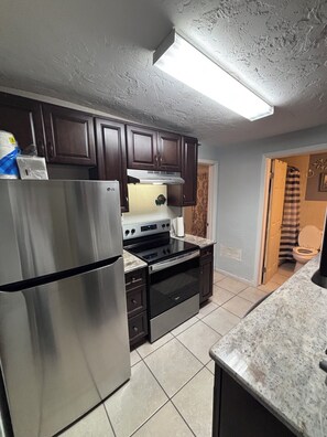Kitchen features modern appliances, an oven, and a microwave, with a large window above the sink.